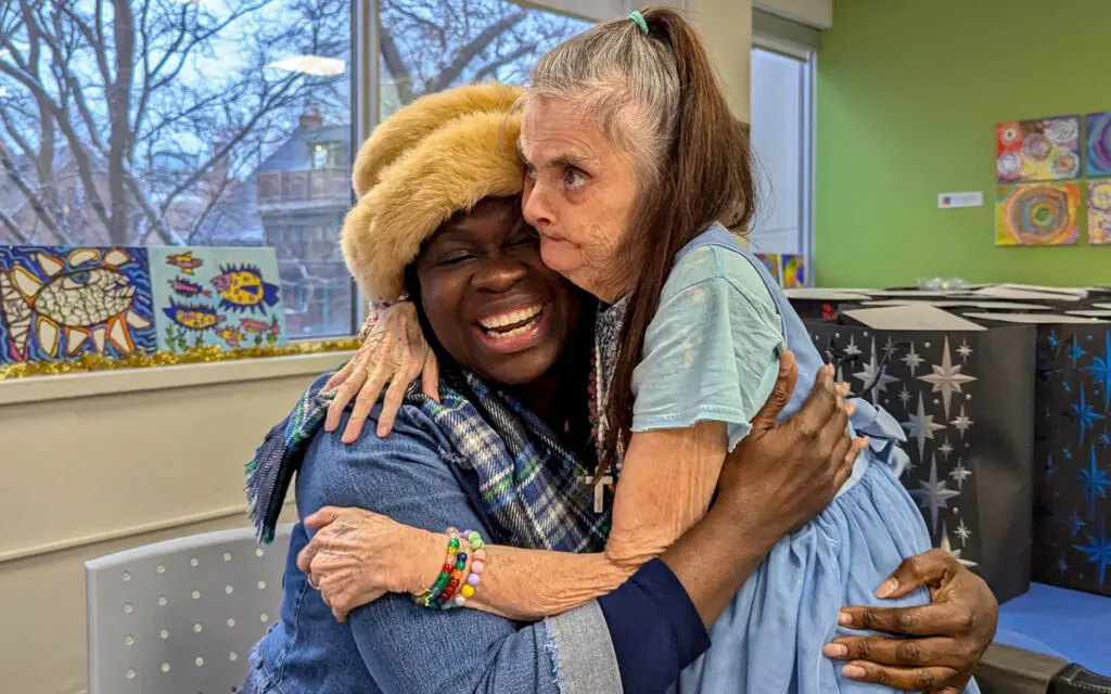 Two people sharing a warm hug and smiling together.
