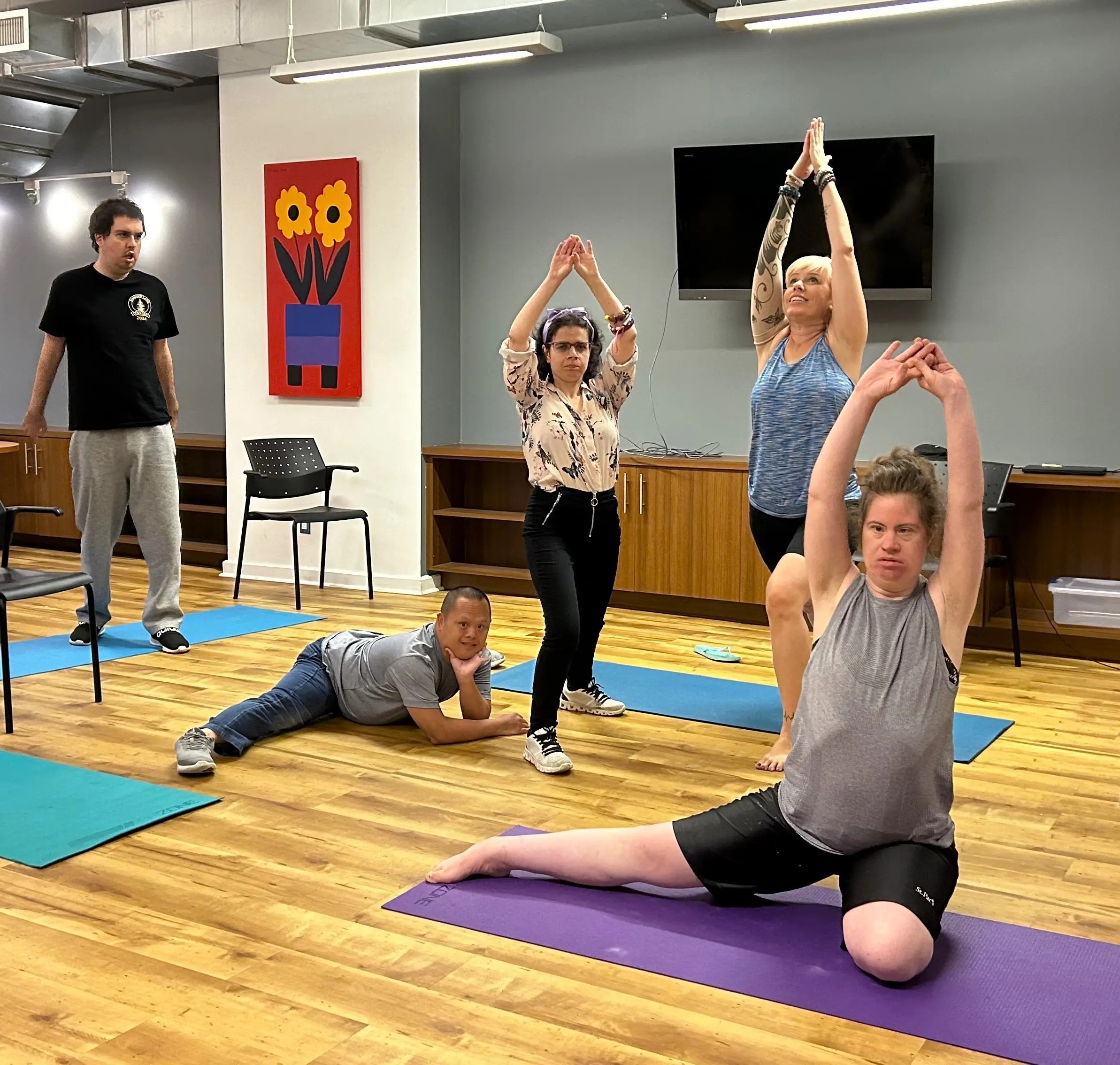 Several participants practice yoga and stretching exercises on mats at Community Junction, guided through a mix of standing, seated, and floor-based poses.