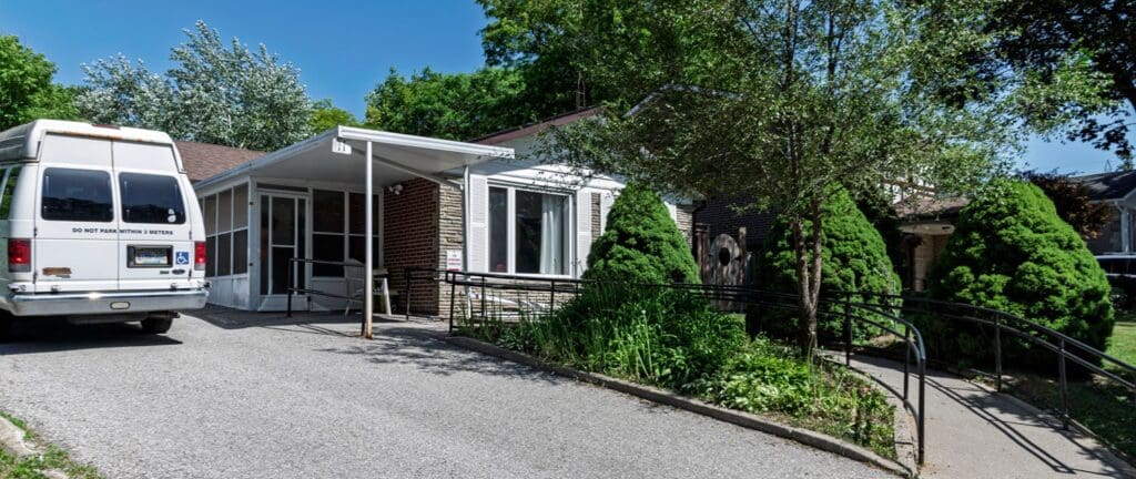 front of a house with a curvy ramp to the door and a big white van in the driveway
