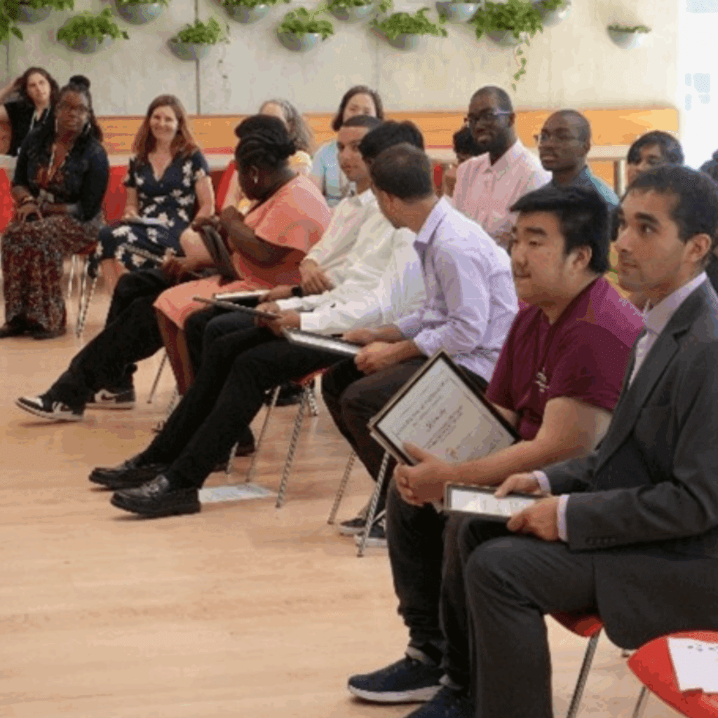 Graduates and Parents sitting in a audience looking forward and happy