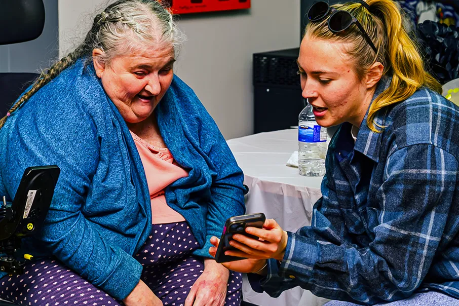 Two people looking at a smartphone together indoors, sharing a moment of connection and engagement.