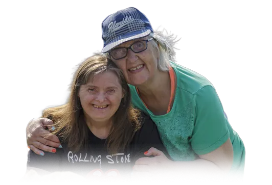 A smiling young woman with an intellectual disability embraced by an older woman