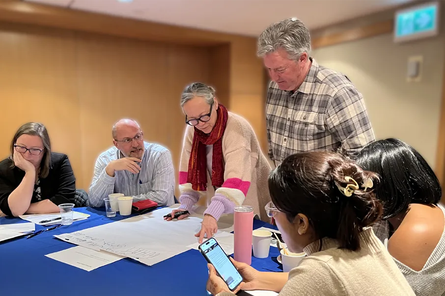 Group of people gathered around a table, collaborating and discussing ideas during a community planning or engagement session.