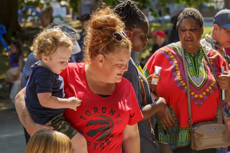 Parents and community members gathered outdoors with children during a family community event.