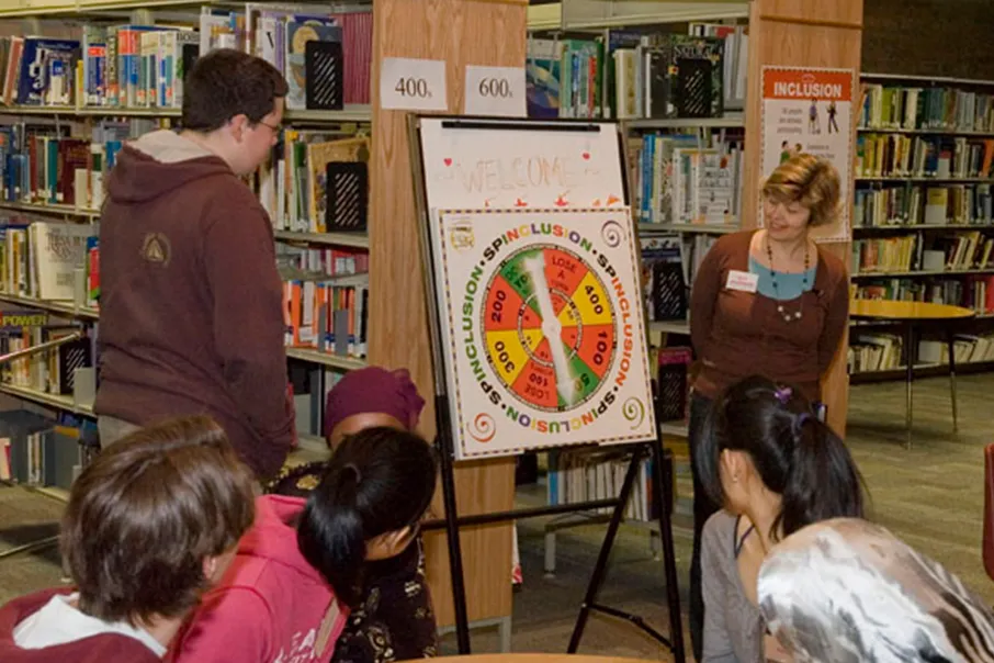 A group of people gathered in a library for an inclusion activity and discussion.