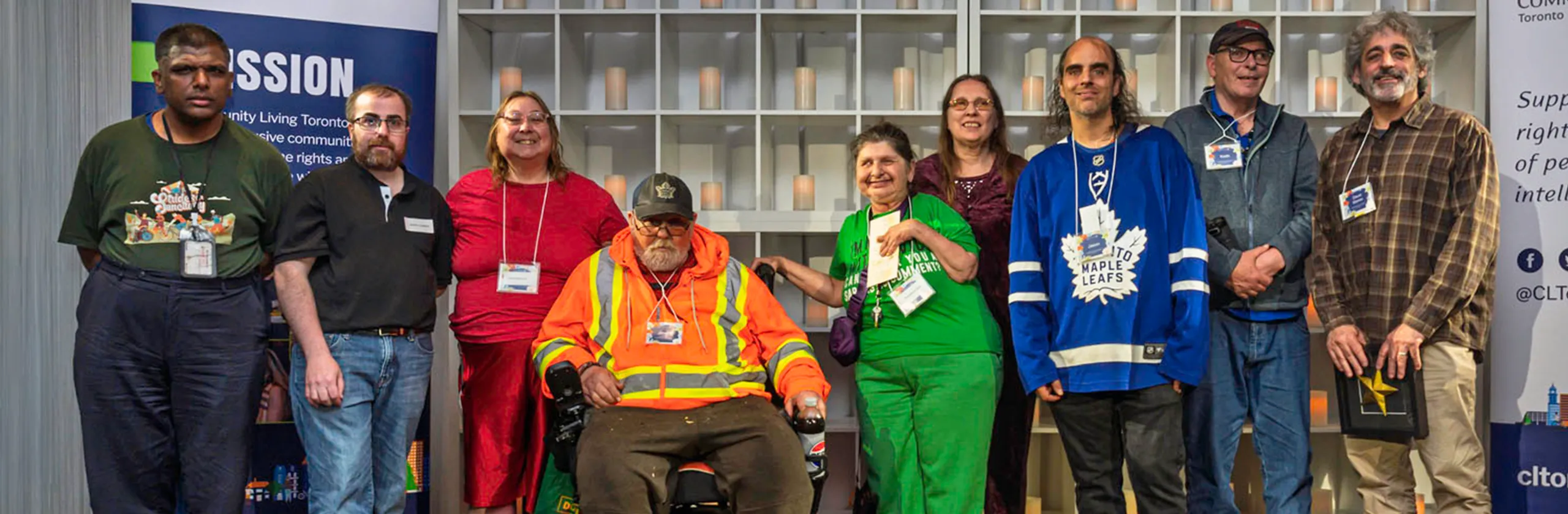 A group of Community Living members pose together on a stage at a Community Living Toronto event and awards gathering.