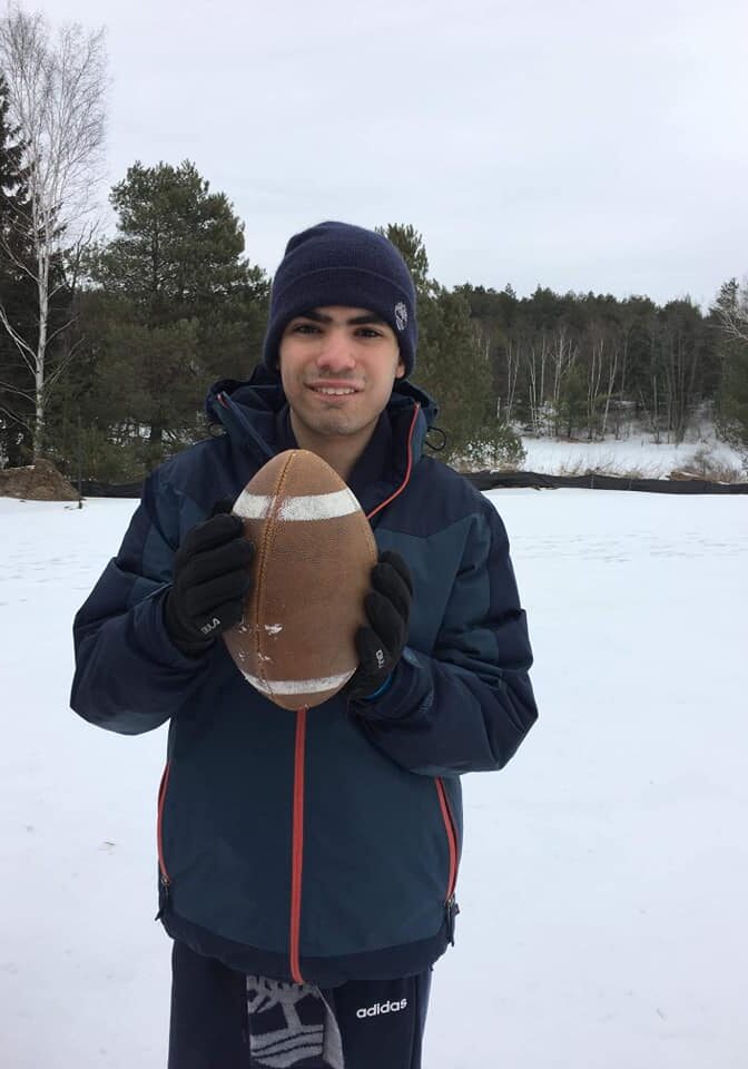 a boy in outside in the winter holding a football